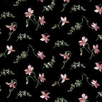 Quilting fabric with small, scattered coral-pink magnolia blossoms on a black background