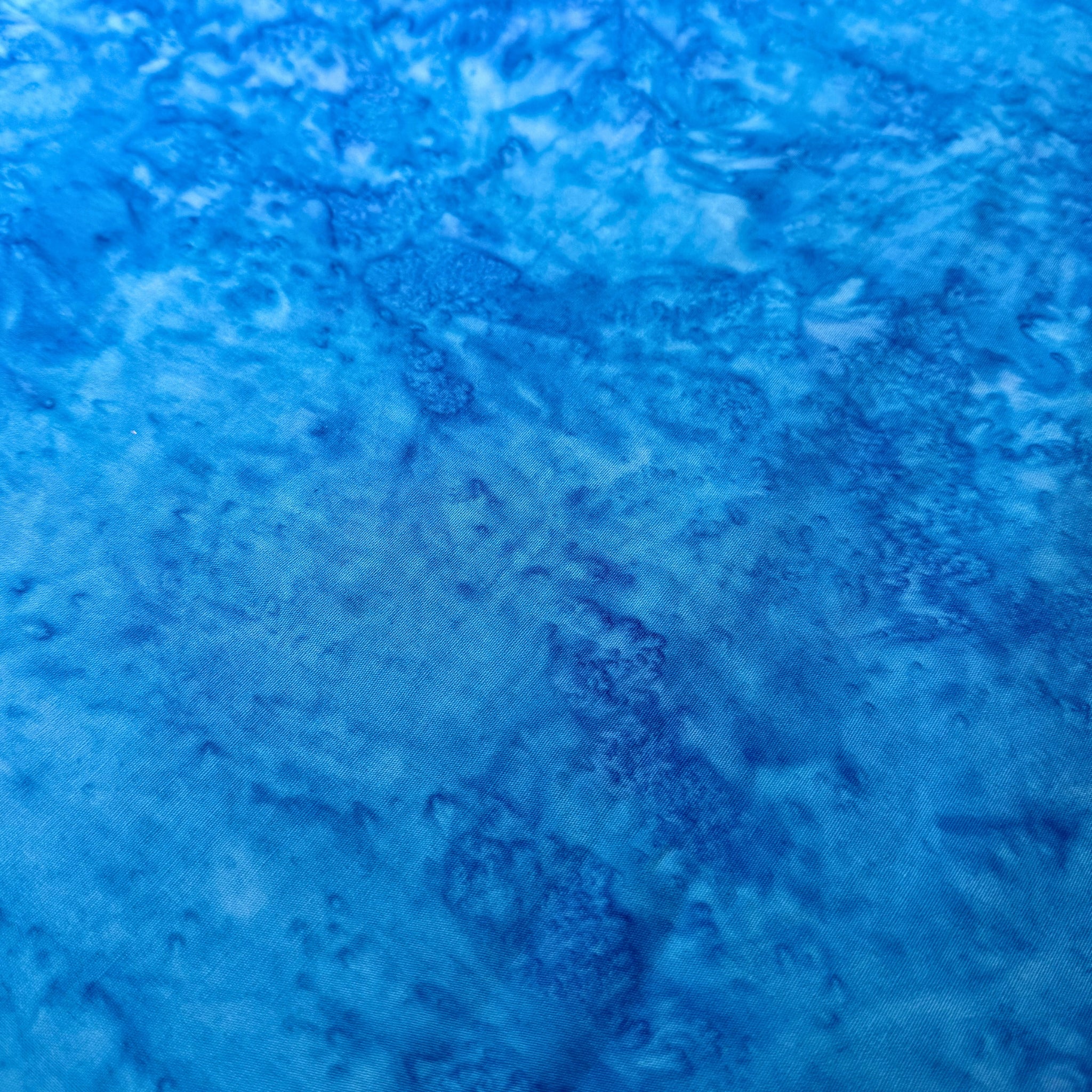 Vivid Bahama blue mottled batik blender fabric with sky blue and cobalt undertones for quilt backgrounds sashing and scrappy batik quilts