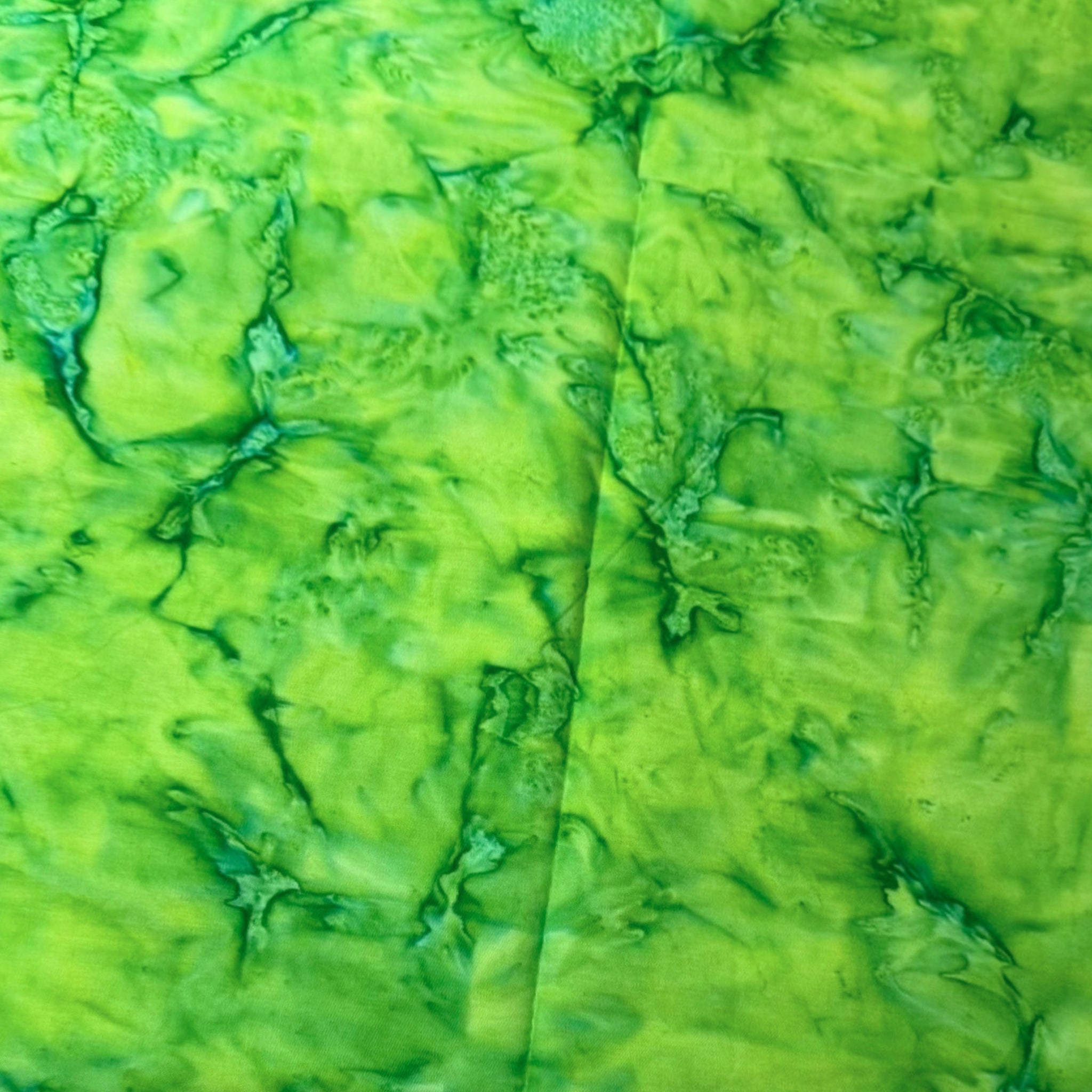 Vivid lime clover green mottled batik blender fabric with emerald and teal undertones for quilt backgrounds sashing and scrappy batik quilts