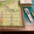 Burrangong Farm Australian panel quilt in progress with kangaroo fence rotary cutter ruler and coordinating fabrics on a cutting mat