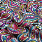 Black fabric with paisley shapes in purple, teal, pink, and lime green outlined in gold metallic
