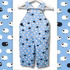 Counting Sheep Following Ewe blue sheep fabric made into children's dungarees overalls with white and black sheep print on blue background