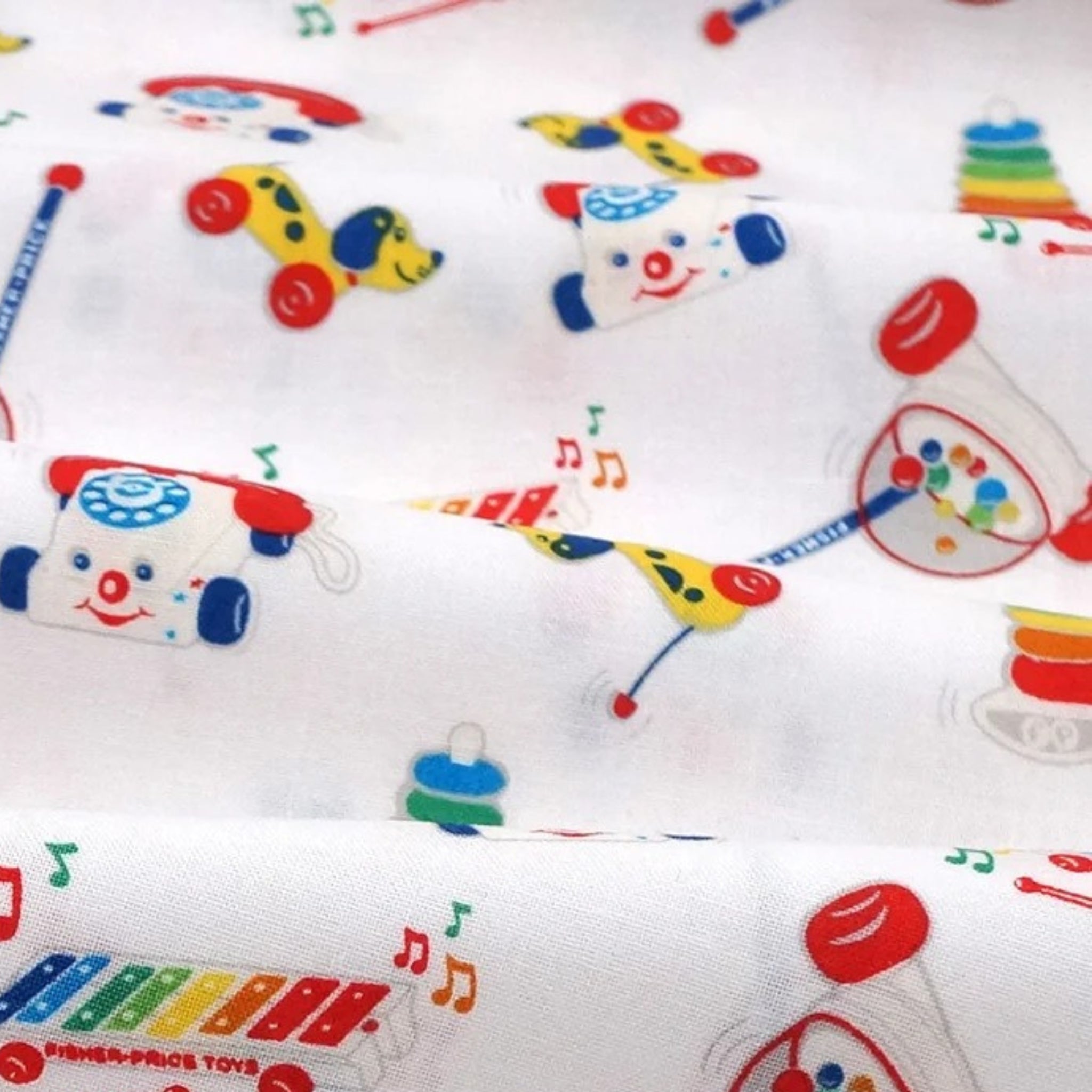 White quilting cotton with bright, tossed Fisher-Price classic toy motifs