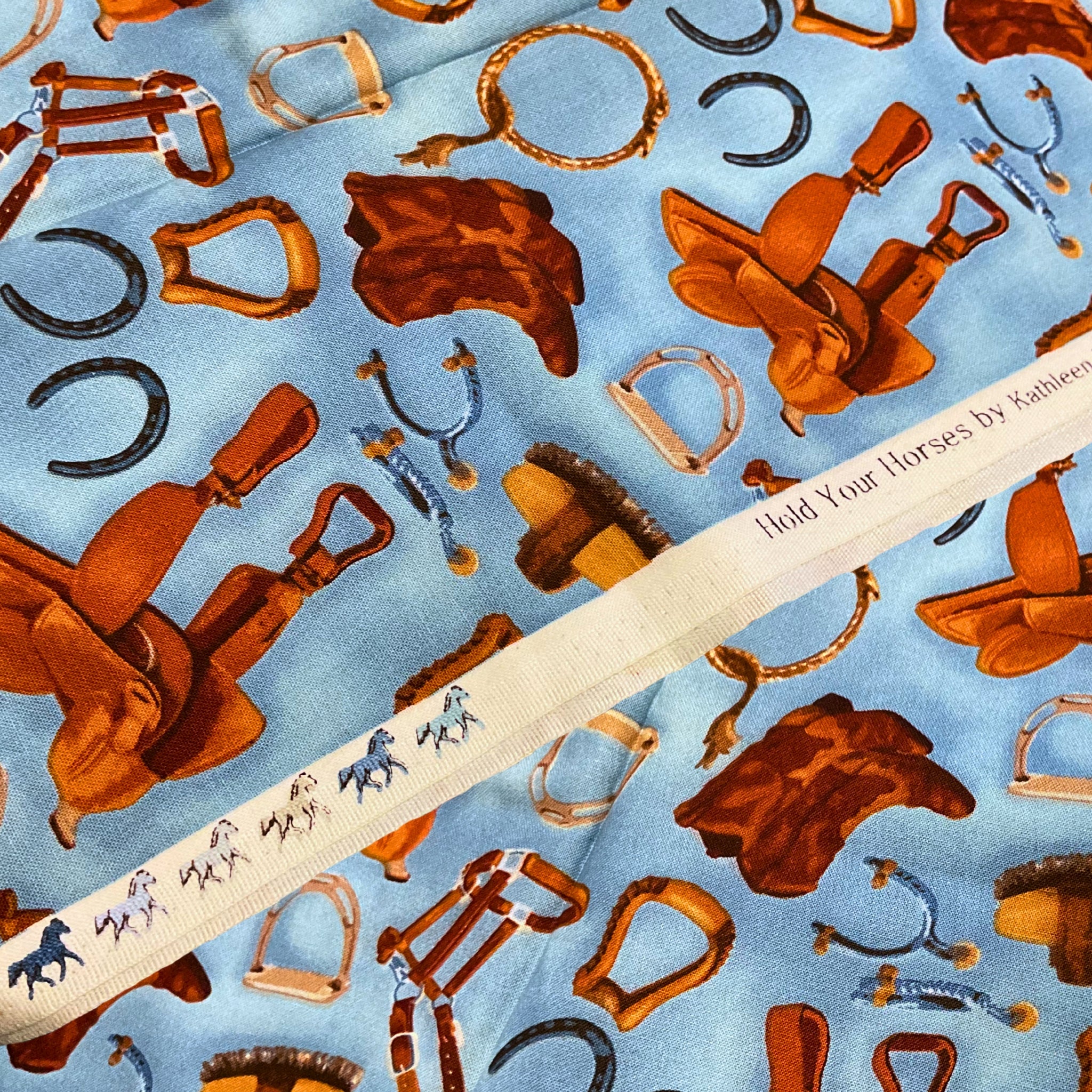 Western riding tack saddles boots horseshoes stirrups blue fabric for horse-themed quilts and equestrian patchwork sewing projects