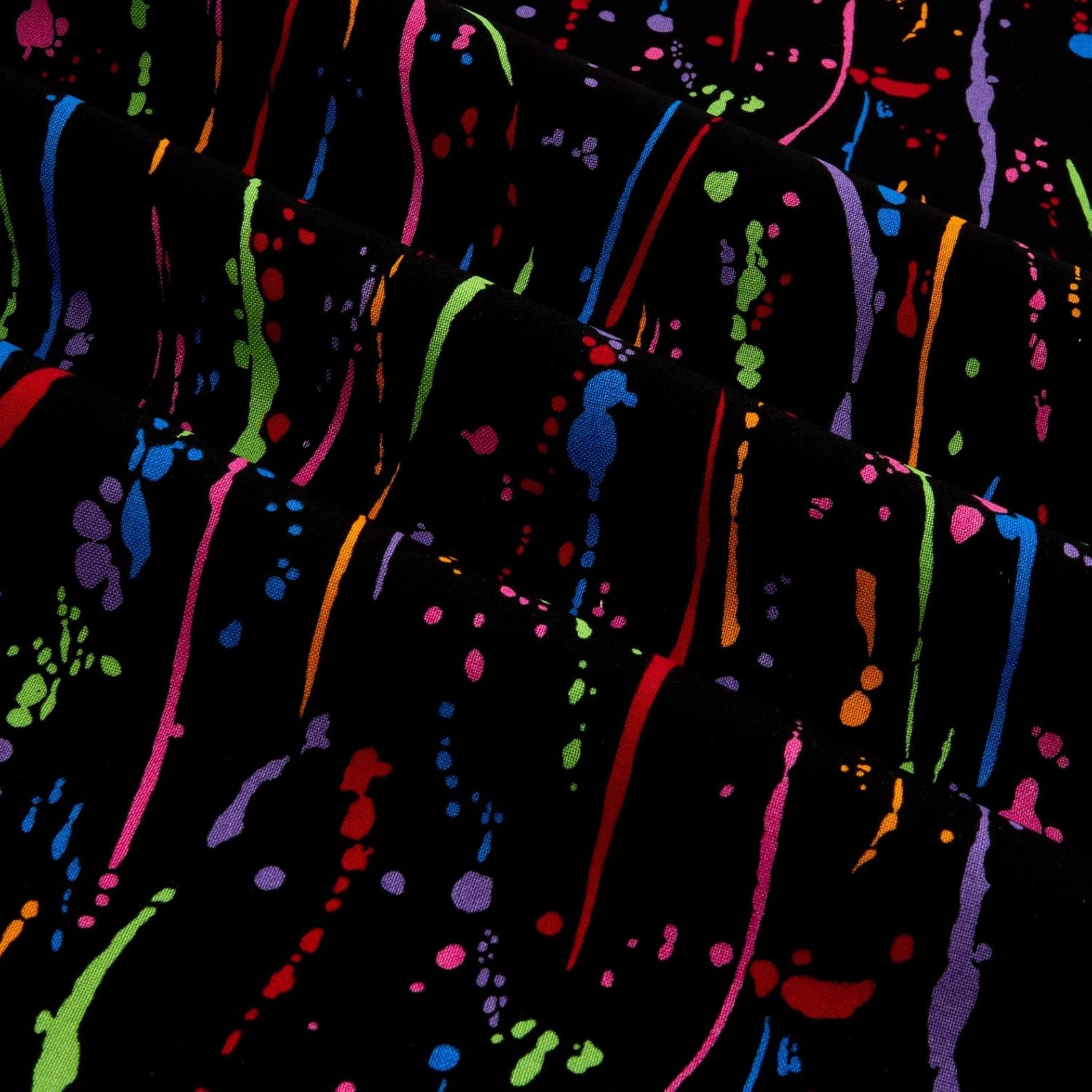Rainbow paint splatters and drops on black fabric for modern quilts and patchwork sewing projects