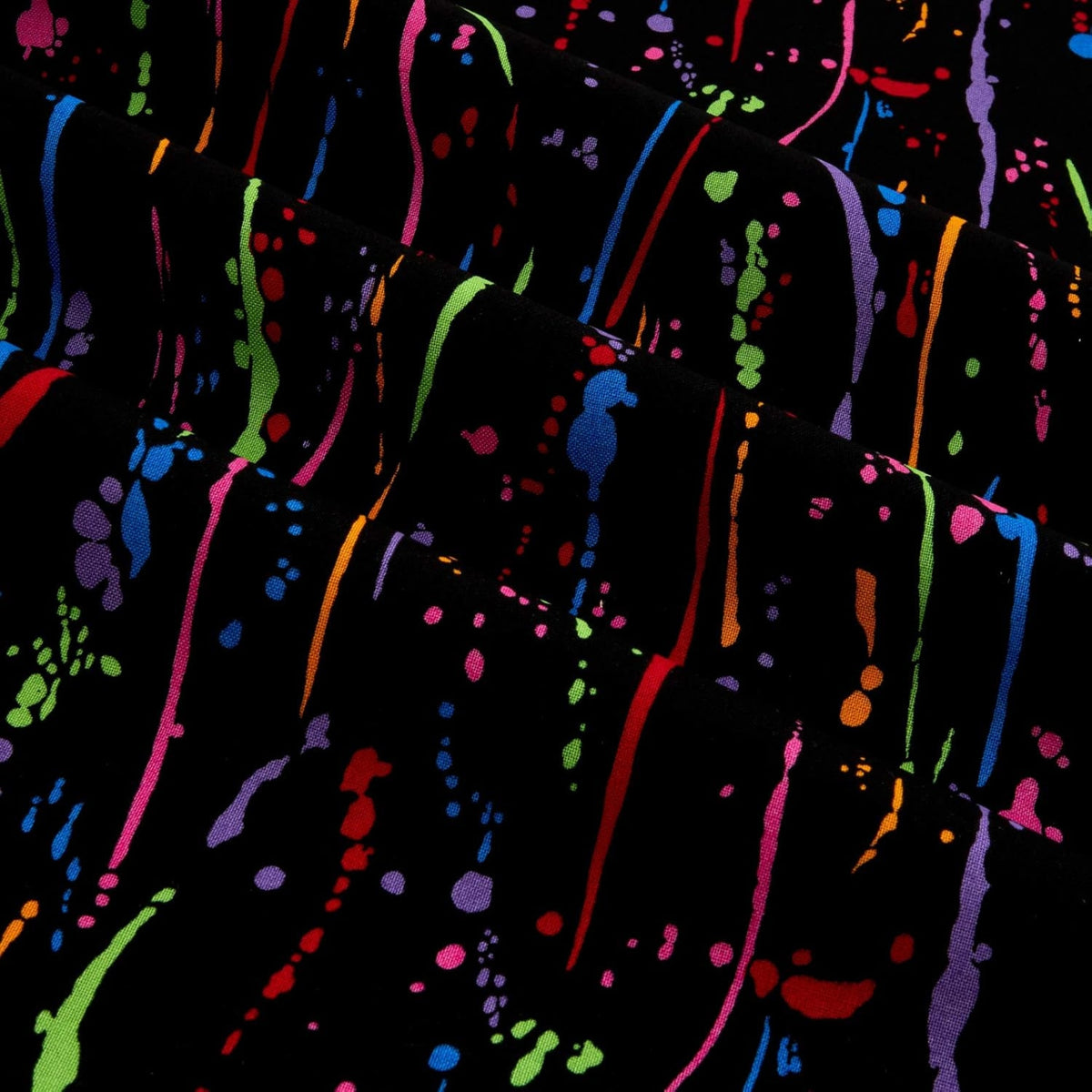 Rainbow paint splatters and drops on black fabric for modern quilts and patchwork sewing projects